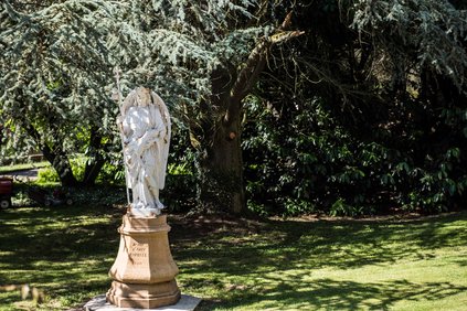 statue religieuse devant un grand arbre majestueux